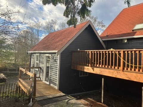 Renovated cottage exterior with red-shingle roof and wood deck