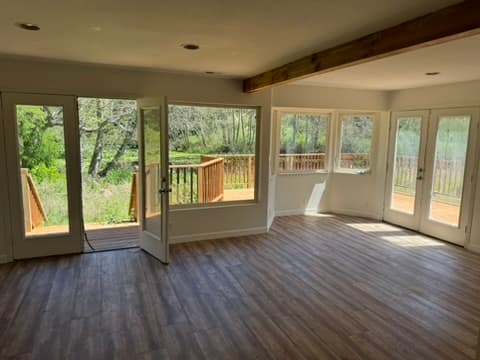 Bright sunroom with hardwood floors opening to deck